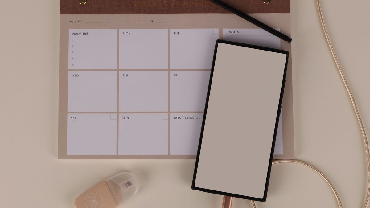 A weekly planner, pen, and notebook laid out on a tidy desk